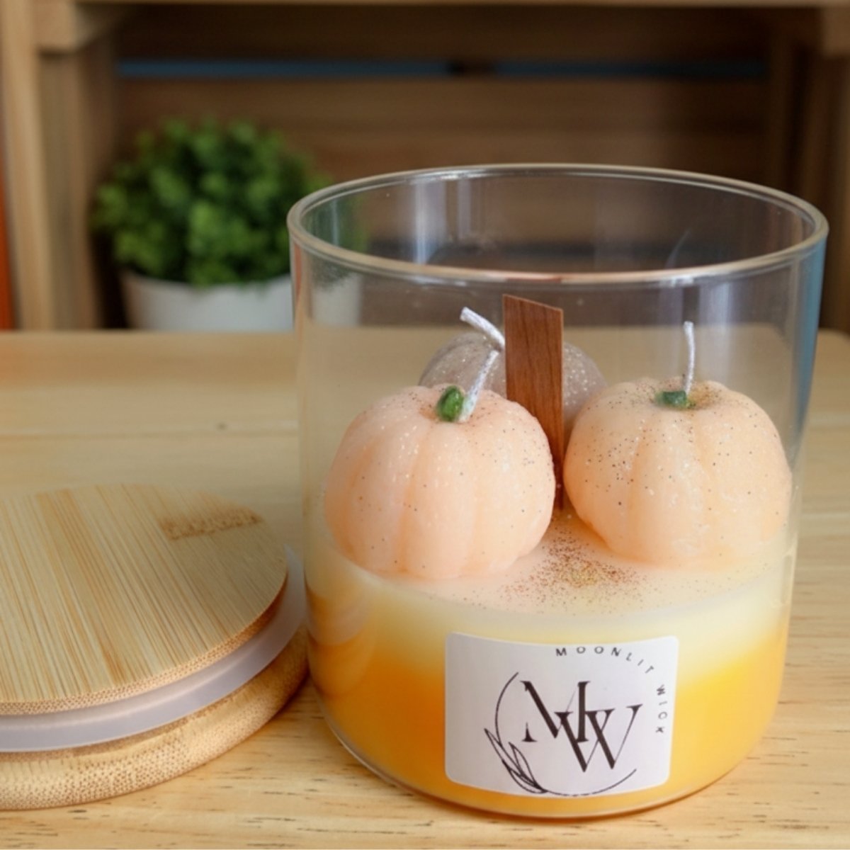 Side view of autumn harvest pumpkin candle with jar and cap, showing multi-colored layers