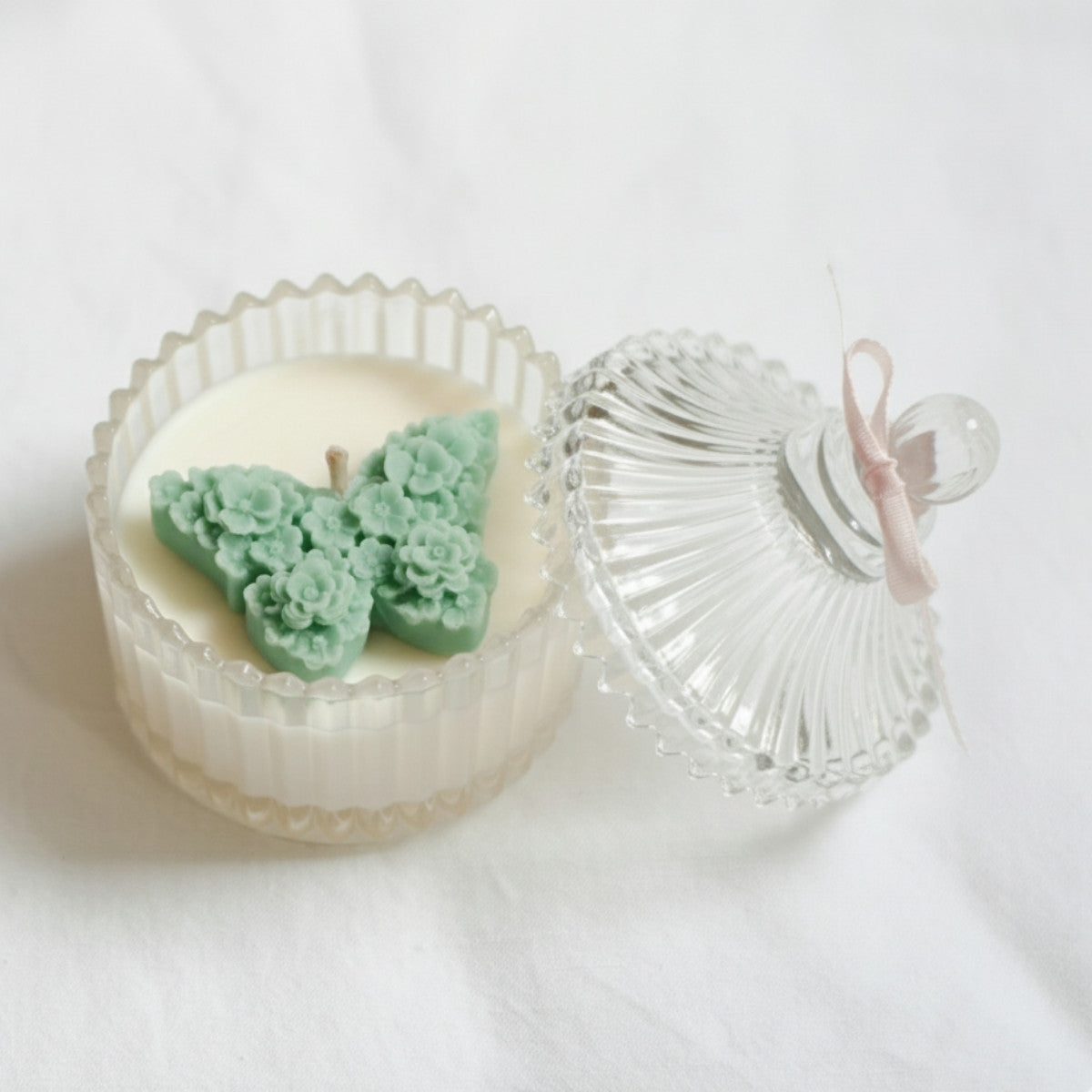 Bliss Candle with butterfly-shaped wax design in a glass container on a white background