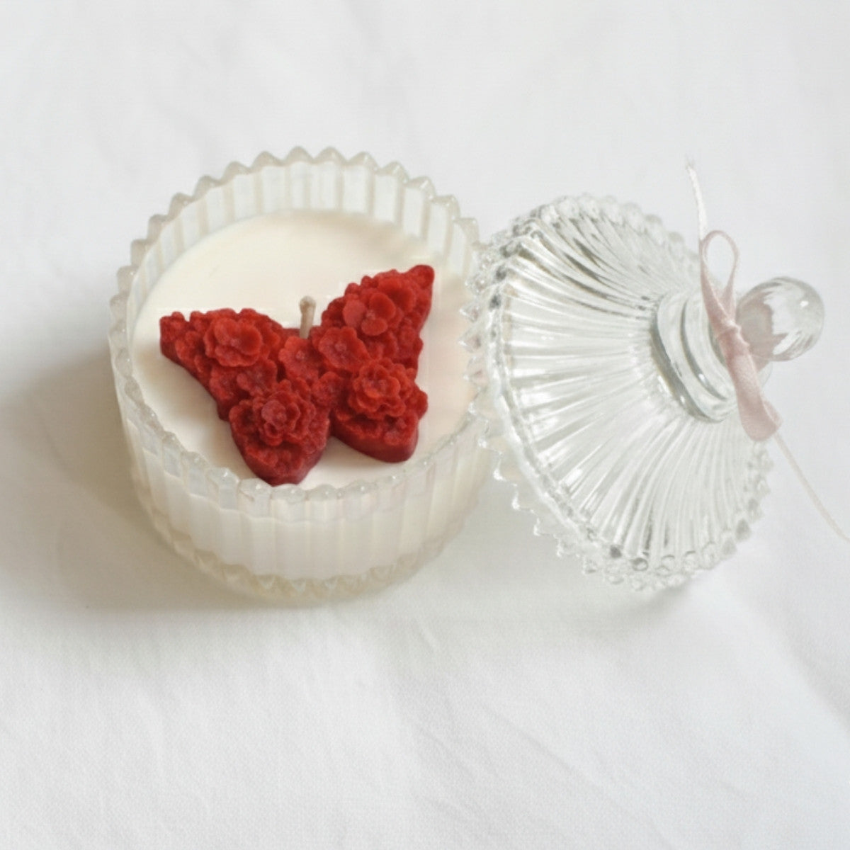 Candle with a red butterfly-shaped design on a white background
