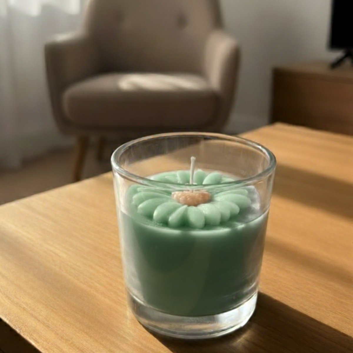 Refreshing mint green candle in a clear glass container on a wooden table with a blurred chair and curtain in the background